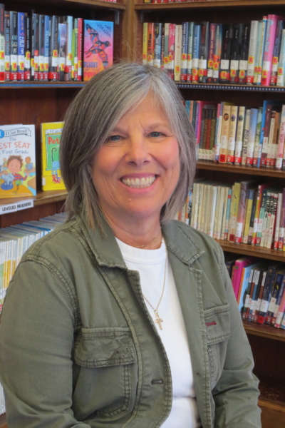 A photo of Deb Graham, librarian at Belmar Public Library, with bookshelves in the background.